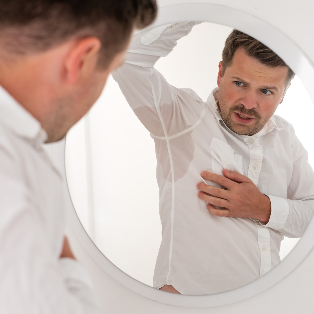 Homme avec taches de sueur visibles sur une chemise blanche — impact de l'hyperhidrose au quotidien